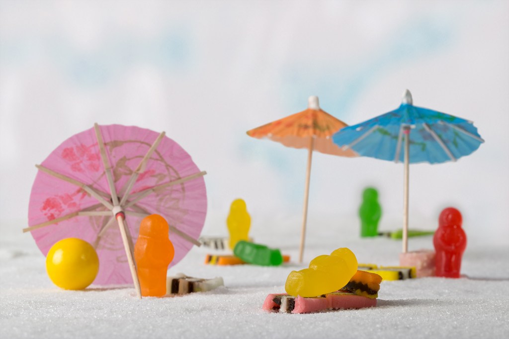 Contemporary artwork by Australian photographer Raymond Mather at ART1 Fine Art Photography. Still Life artwork featuring cocktail umbrellas and jelly babies in a beach scene.